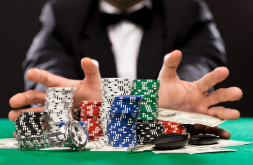 man's hands about to grab money and poker chips from poker table